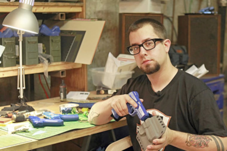Jon Hauptman, founder of PHLSTER, with one of the custom handgun holsters he manufactures in a basement workshop in lower Kensington. What started as a hobby has morphed into a niche business, with gross sales this year expected to reach $50,000. (AKIRA SUWA / Staff Photographer)