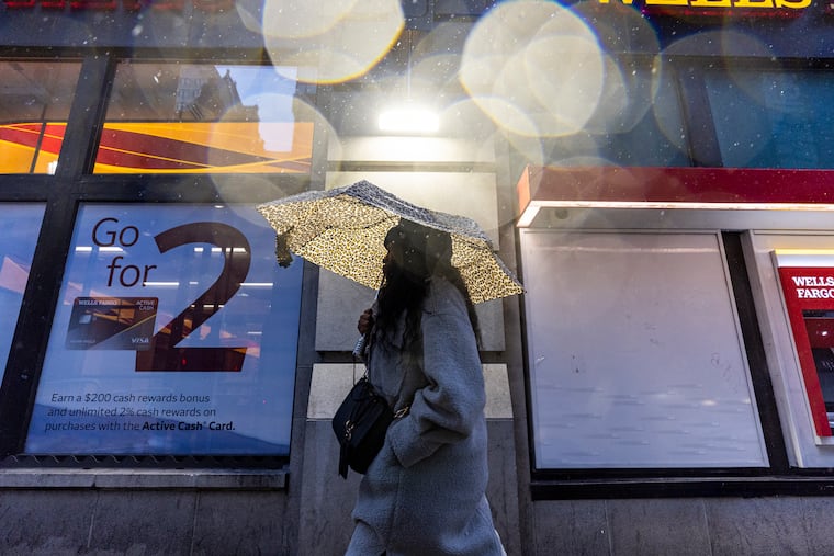 A person walks along the sidewalk at 15th and Chestnut, as rain pours in Philadelphia.