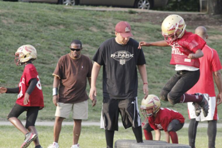 A youth team practices on the football field in Hunting Park. Eagles quarterback Michael Vick donated $200,000 for renovation of the decrepit facility. (Jessica Parks / Staff)