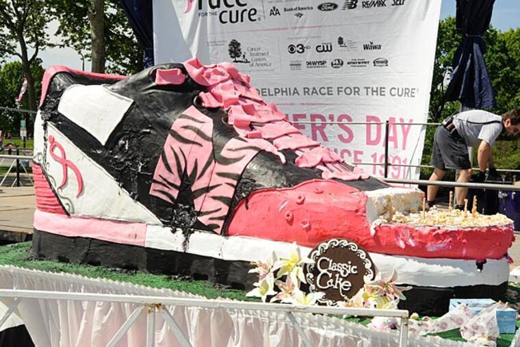 The partially eaten giant cake in the shape of a sneaker is free for the taking to breast cancer survivors near the main stage of the Susan G. Komen Race for the Cure. (Ron Tarver/ Staff Photographer)