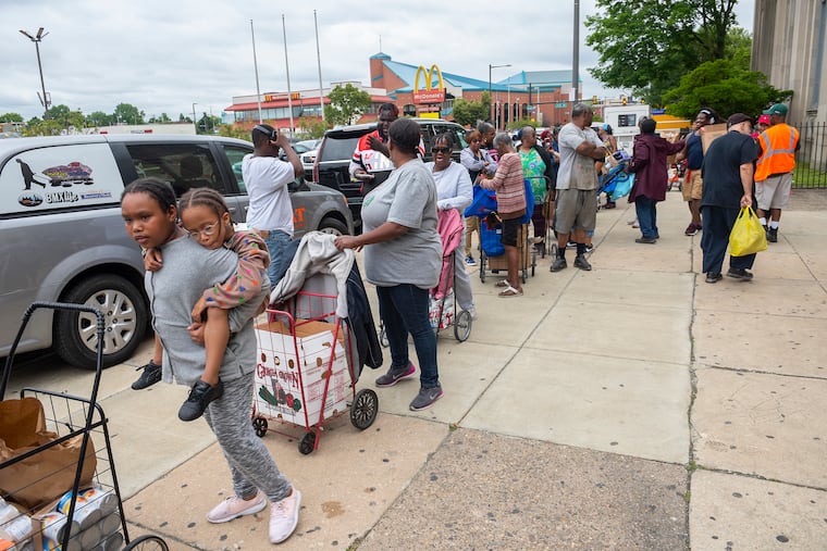 People queue up during a food giveaway at Dobbins High School in North Philadelphia this summer.