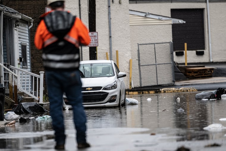 A worker assess the flooding damage on Florence Avenue near the Darby Creek in Collingdale in December, an especially rainy month in the region.