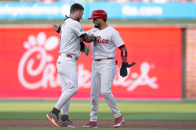 Luis Arraez (right) in congratulated by Bryce Harper after hitting an RBI single his first at-bat during his debut with the team in the first inning.