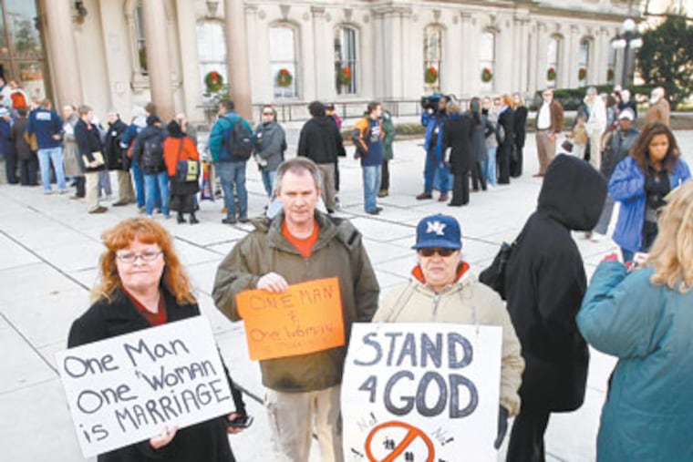 Opponents hold signs against gay marriage as people wait in line to go into the New Jersey Statehouse on Monday in Trenton, N.J. (AP Photo/Mel Evans)