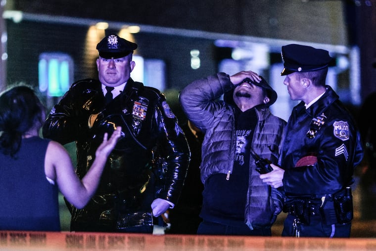 Distraught onlookers speak to police after a triple homicide in the Mayfair section of Philadelphia on Monday night.