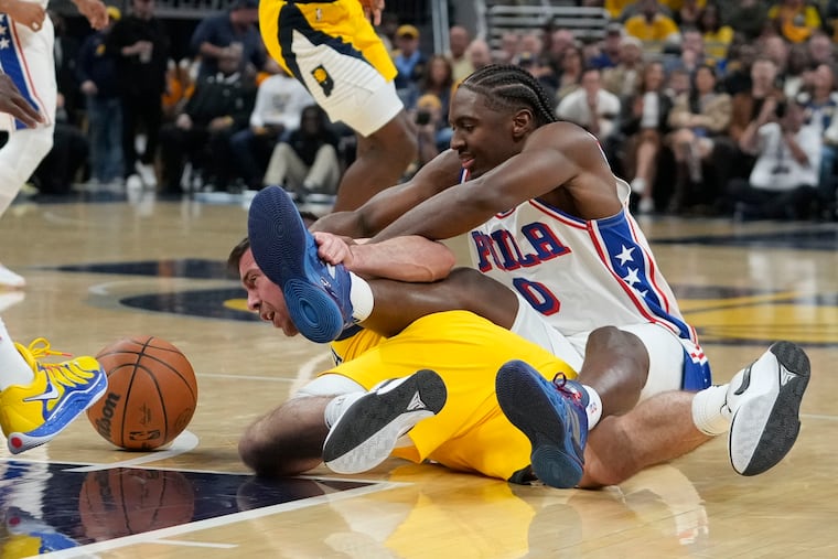 The Sixers’ Tyrese Maxey (0) fights for a loose ball with Indiana’s T.J. McConnell.