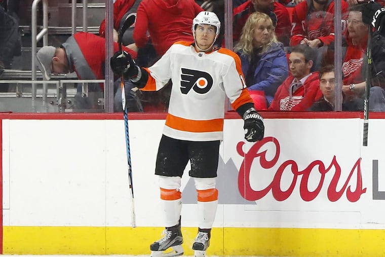 Travis Konecny waits for teammates to help celebrates his game-winning goal in overtime to beat Detroit on Tuesday.