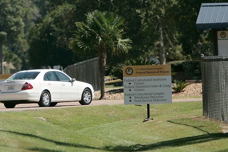 A person drives through the gates of a federal prison in Oakdale, La. The federal Bureau of Prisons is locking all its 146,000 inmates in their cells for the next two weeks in an unparalleled effort to slow the spread of the coronavirus, as the focus shifts to the Louisiana compound, where two inmates have died and nearly 20 others remain hospitalized.