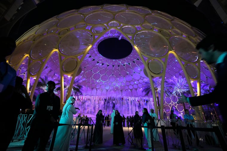People walk near a lit-up Al Wasl Dome at Expo City at the COP28 U.N. Climate Summit, Friday, Dec. 1, 2023, in Dubai, United Arab Emirates.