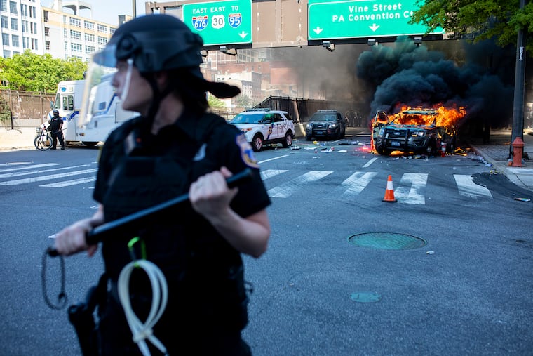 Philadelphia police make a wall to block protestors from approaching a burning Pennsylvania State Police car near the intersection of Broad and Vine Streets during May 30, 2020, protests over the death of George Floyd.