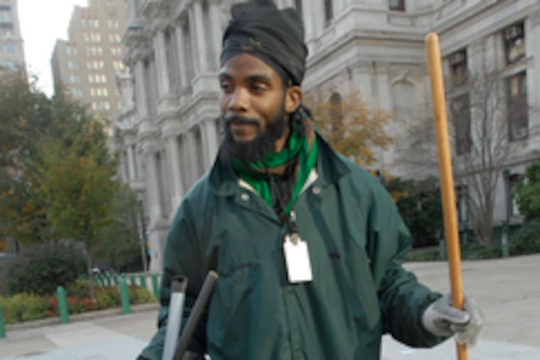 City worker Clarence Anwar cleans up debris left around City Hall after the World Series parade. He was on the job Friday as well as yesterday.