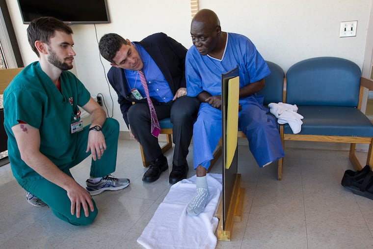 At Temple University Hospital, Arnold Carlton, whose left leg was removed below the knee, undergoes mirror therapy for phantom pain with attending physician Eric Altschuler and physical therapist Mark McNutt.