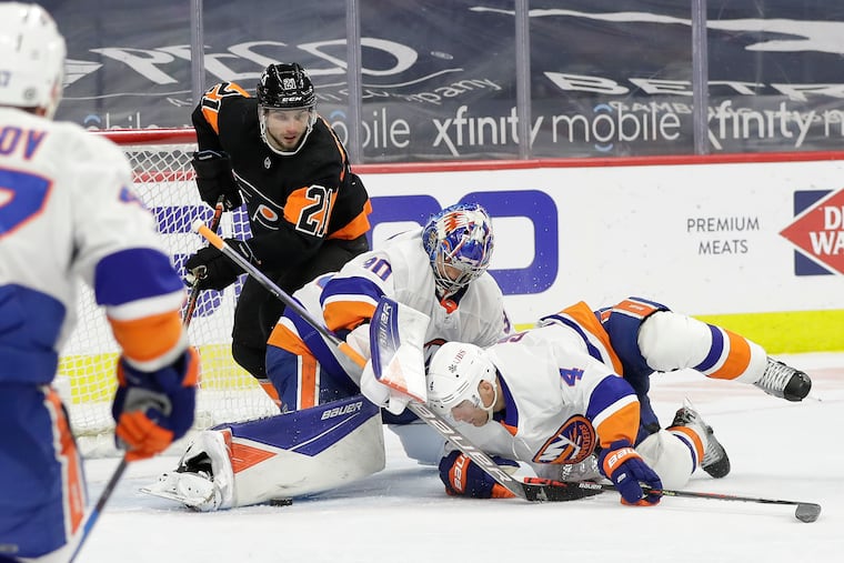 New York Islanders goalie Ilya Sorokin and defenseman Andy Greene (right) try to cover the puck as the Flyers' Scott Laughton looks for a rebound in a game last season. The Isles are the Metropolitan favorite this season.