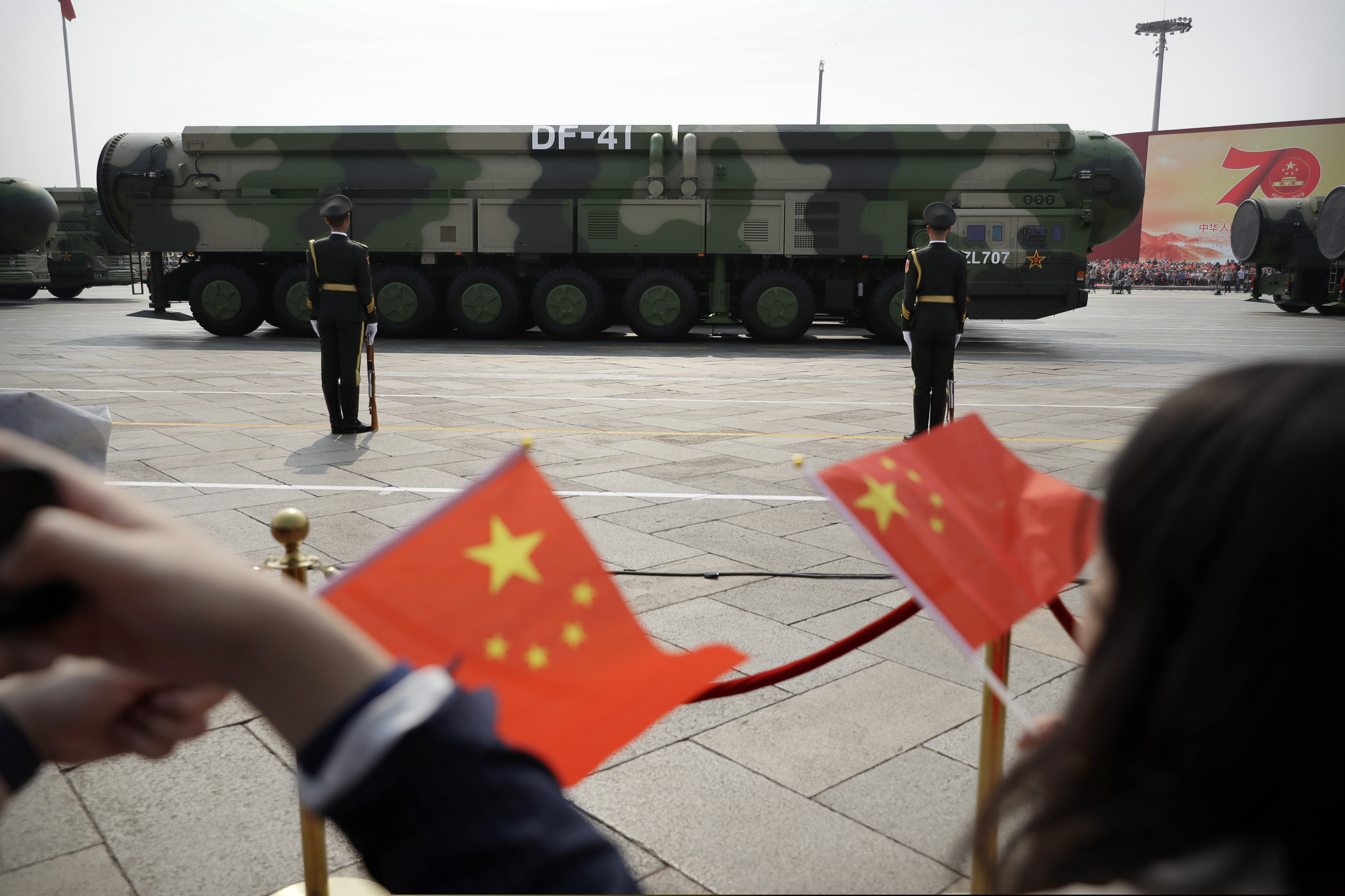 Spectators waved Chinese flags as military vehicles carrying DF-41 ballistic missiles rolled during a parade to commemorate the 70th anniversary of the founding of Communist China in Beijing, Oct. 1, 2019.