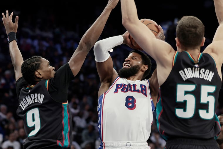 Sixers Paul George (center) is fouled by the Pistons Ausar Thompson (left) in the first half of Saturday's game at the Xfinity Mobile Arena.