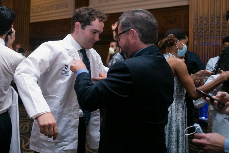 Cristian DeSimone has his white coat put on him during a ceremony for Jefferson medical school students in July. The students are beginning their medical school journey coming off the worst of the pandemic.