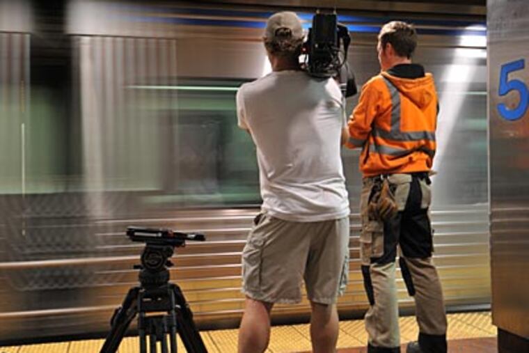 Host Sean Riley and a cameraman watch a SEPTA train pass by. (National Geographic Television)