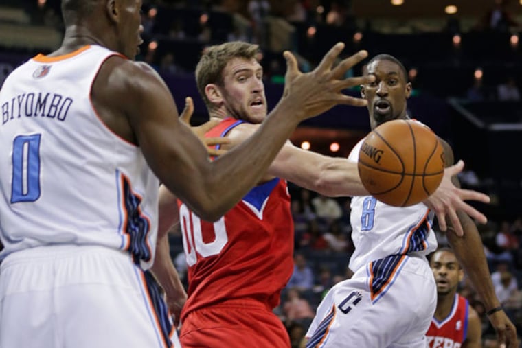 Bobcats' Ben Gordon, right, passes the ball around Philadelphia 76ers' Spencer Hawes, center, to Bismack Biyombo, left, during the first half of an NBA basketball game in Charlotte, N.C., Friday, Dec. 6, 2013. (Chuck Burton/AP)