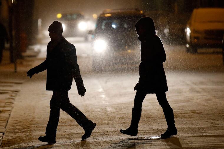 A couple walk across 10th Street near Lombard Street just after the snow arrived Friday.