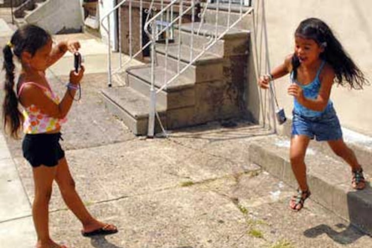 Elani Rodriquez, 5, is too quick for Centro Nueva Creación classmate Siani Rodriquez, 6, to snap her picture. Children at the after-school and summer camp program look for good in the often-derided neighborhood. (Tom Gralish / Staff)