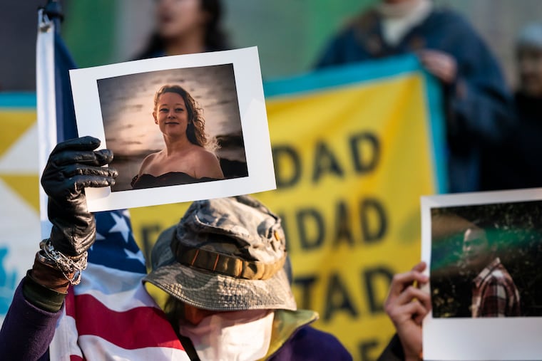 A protester holds up a picture of Renee Good, who was killed by an ICE agent in Minneapolis, as people gather for a vigil at City Hall on Thursday.