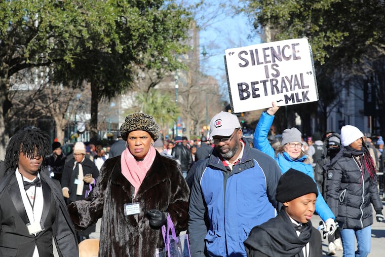 A marcher holds up a sign at a march and rally at the South Carolina Statehouse to honor Martin Luther King Jr. on his holiday on Monday, Jan. 20, 2025, in Columbia, S.C.