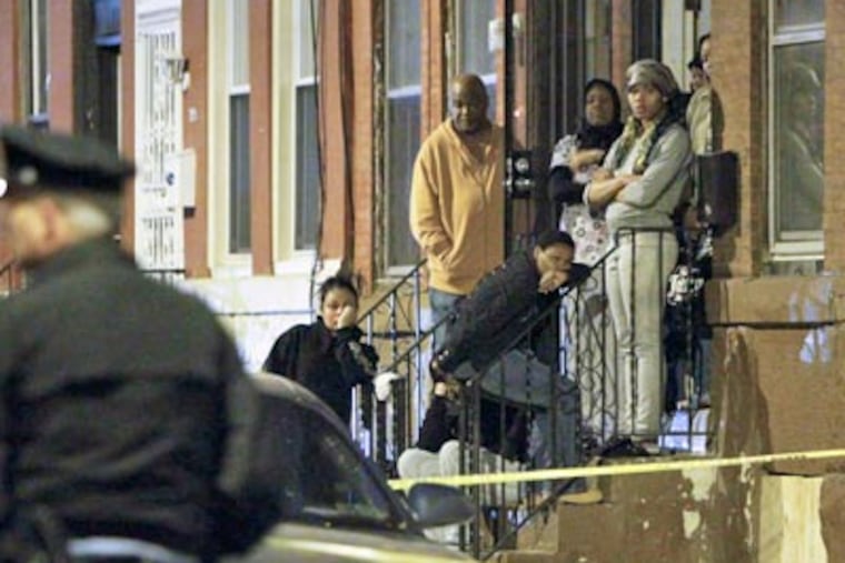 Family members watch as police investigate a home-invasion robbery by as many as five masked men in the Fairhill section of North Philadelphia that left one man dead. JOSEPH KACZMAREK / For the Daily News