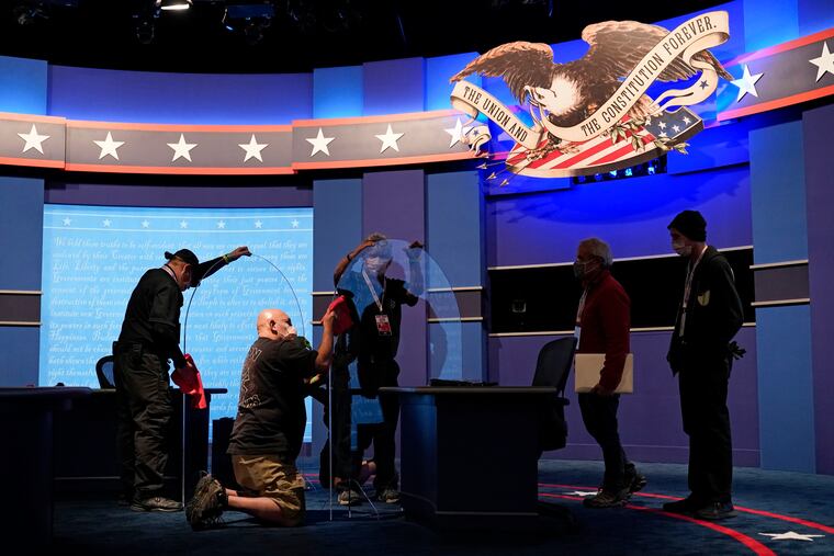 Workers clean protective plastic panels onstage between tables for Vice President Mike Pence and Democratic vice presidential candidate Sen. Kamala Harris ahead of the vice presidential debate.