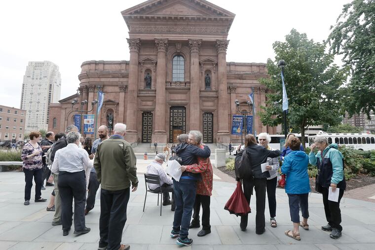 Judy Heffernan (center, facing camera) and others hug after a prayer service and vigil on the sidewalk opposite Cathedral Basilica SS. Peter and Paul in Philadelphia Saturday, in one of many protests throughout the country stemming from the recent Pennsylvania grand jury finding of rampant sex abuse by clergy over seven decades.