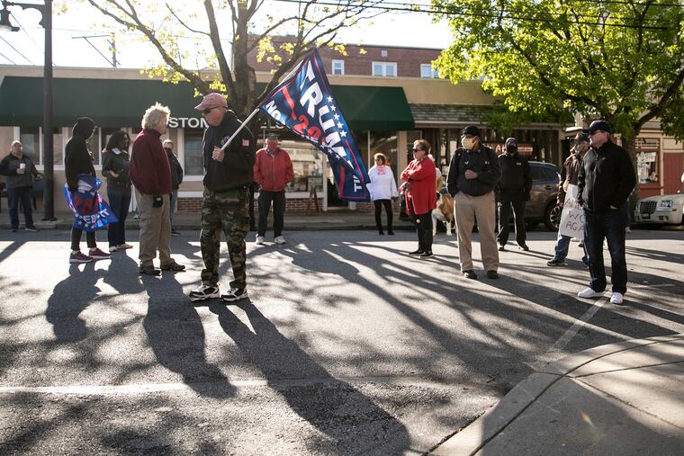 People stand in the street during a small rally outside of Giovanni's Barbershop in Media, Pa. on Saturday, May 09, 2020. Nichole Missino, owner of the shop, was planning on defying state orders and reopening on Saturday, but instead decided to hold a rally. She says government officials do not understand the pressure that small businesses are under because of the safety orders around the pandemic.