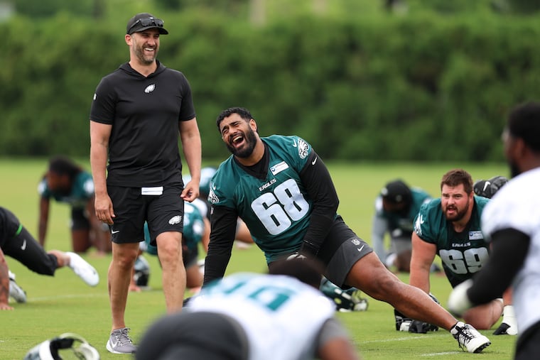 Eagles head coach Nick Sirianni (left) and tackle Jordan Mailata (68) laugh during mandatory minicamp last week.