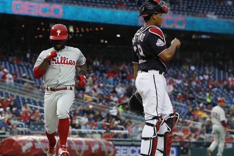 Odubel Herrera, left, scores off a single hit by teammate Carlos Santana as the Phillies drilled the Nationals in Washington.