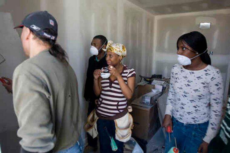 Construction instructor Chris Pisano offers painting lessons to (from left) Kevin Kennedy, Keliah Shelton, and Sharita Paul. The students attend YouthBuild Philadelphia Charter School, where the curriculum also incorporates the green techniques that many builders are employing.