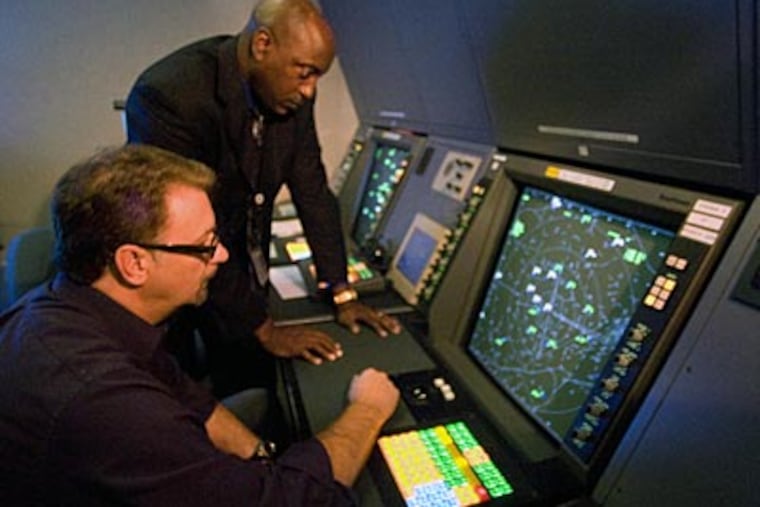 Arthur Sullivan, (standing) an FAA program manager for surveillance and broadcast services, looks with Dave Urban, FAA support specialist, at a demonstration of the NextGen system. (Clem Murray / Staff Photographer)