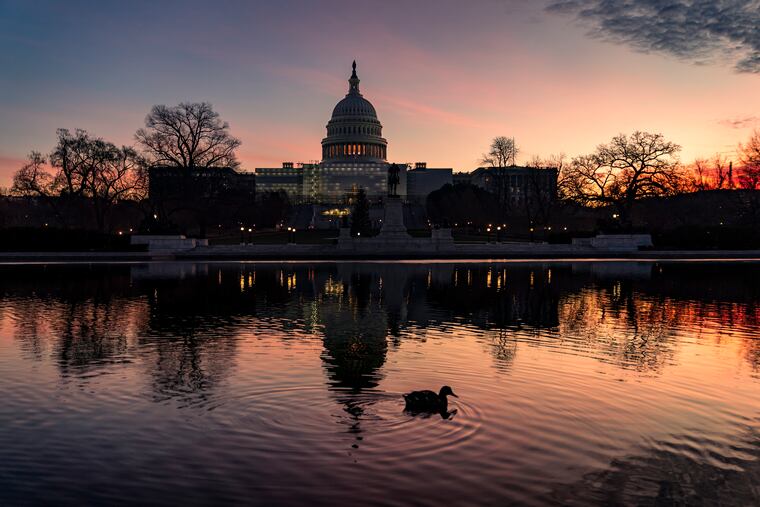The sun rises behind the Capitol in Washington.