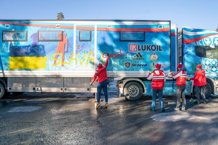 Members of the Russian cross-country national team try to remove a Ukrainian flag and writing reading "Glory to Ukraine" from the side of the team trailer in Holmenkollen. Norway, on Wednesday.