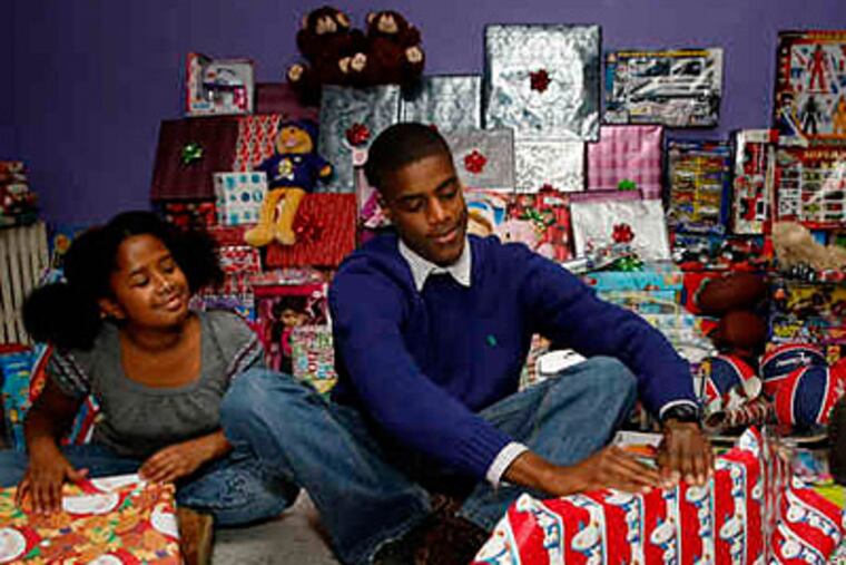 Nehemiah Davis, 22, wraps presents while one of his sisters looks on. He opened a produce stand at 19, and soon after started Asset Cleanouts, which removes junk from clients' homes and businesses. (Michael S. Wirtz / Staff)