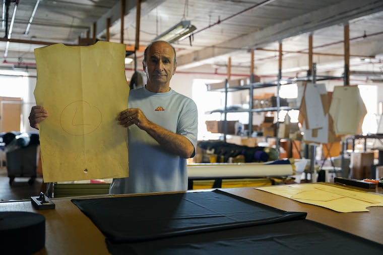 Efraim Nathan, owner of Sweat It Out, poses for a photograph holding a fabric cutting template for a shirt at the Sweat It Out cutting and sewing production location in Norristown, Pa., on November 18, 2021. Sweat It Out custom sews “Cool Compression” tight sports athletic wear for pro NFL, NHL, NBA and MLB players.