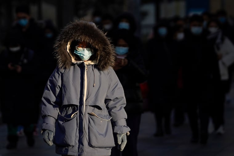A woman wearing face masks to help curb the spread of the coronavirus heads for work during the morning rush hour in Beijing, Monday, Jan. 4, 2021.