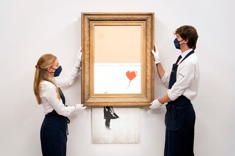 Art handlers at Sotheby's auction house hold Banksy's 'Love is in the Bin' last week, before it returns to auction.