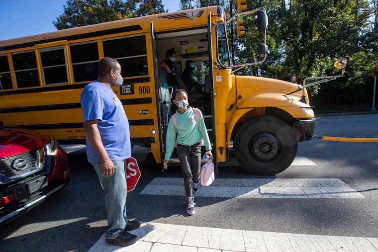 Robert Brown, building engineer, doubles as crossing guard, watching as a young girl gets off a bus outside Wissahickon Charter School in Philadelphia Sept. 10.