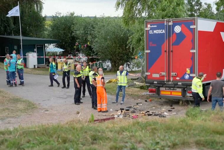 In this frame grab taken from video, policemen and rescuers stand at the site where a truck plowed into a gathering in the village of Nieuw-Beijerland, Netherlands, Saturday Aug. 27, 2022. A truck drove off a dike and slammed into a community barbecue in a village south of Rotterdam on Saturday killing and injuring several people.