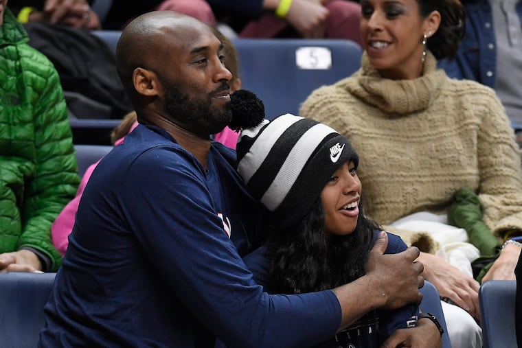 Kobe Bryant and his daughter Gianna watch the first half of an NCAA college basketball game between Connecticut and Houston in Storrs, Conn. on March 2, 2019. A public memorial service for Bryant, Gianna and seven others killed in a helicopter crash is planned for Monday, Feb. 24, 2020, at Staples Center in Los Angeles.