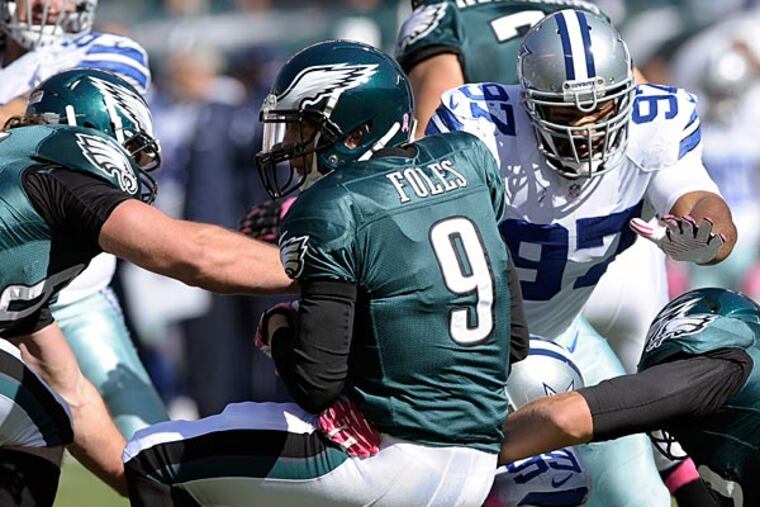 Eagles quarterback Nick Foles is sacked by Dallas Cowboys defensive end George Selvie (99) as defensive tackle Jason Hatcher (97) helps during the first half. (Michael Perez/AP)