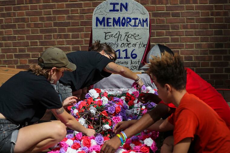 (Clockwise from left) Catalyst Twomey, Jamaal Henderson, Noble Henderson and Billy Boyer lay down roses, which represent people in Philadelphia who died of drug overdose in 2018, outside the Federal Courthouse in Center City in September 2019.