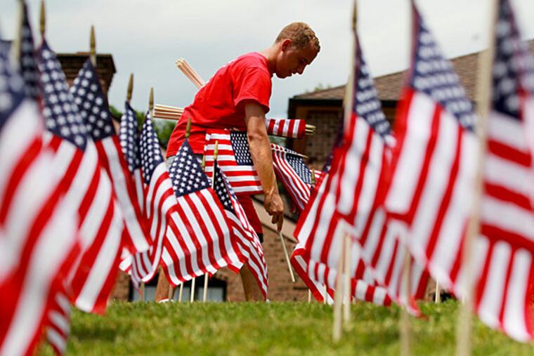 File: Michael Ciavarelli places one of 1,500 American flags that he and his father planted in the front lawn of Ciavarelli Funeral Home in Ambler Thursday, July 3, 2014. MICHAEL BRYANT / Staff Photographer