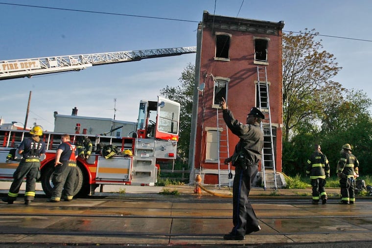 Philadelphia Fire and Police Department personnel investigate a fatal fire along
W. Girard Avenue near 49th Street on Friday morning. The fire was in a boarded-up row house where a woman was found dead. The dog and handler are with the Camden County Fire Marshal's office. (Alejandro A. Alvarez / Philadelphia Daily News)