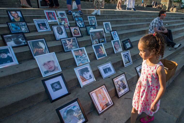 Elisha Sharpe walks by photos of the victims of gun violence placed on the Art Museum steps in June 2017.