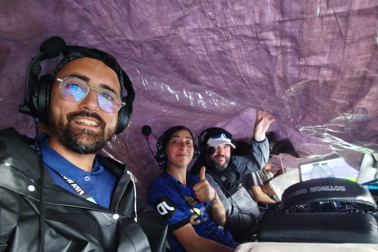 From left, France Info radio broadcaster Julien Froment, technician Virginie Lorda, and broadcaster Xavier Monferran with the tarp over their heads during their call of the France-Iraq game on Monday.