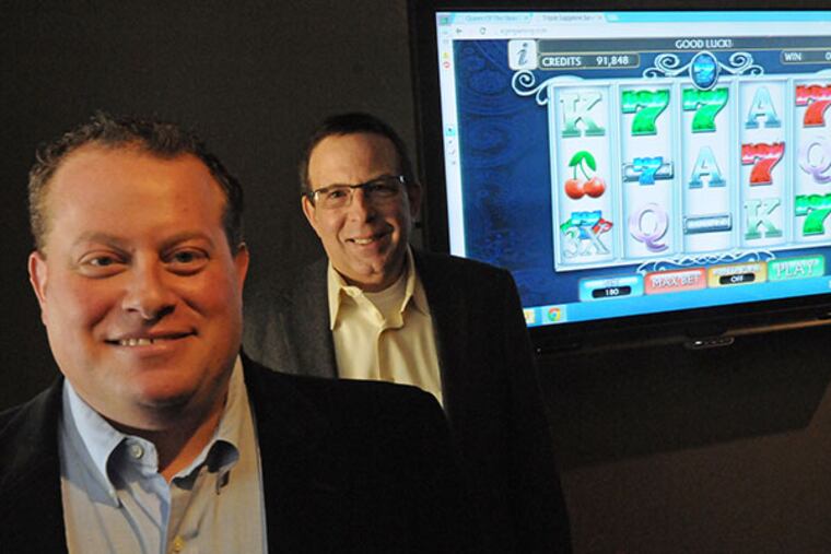 President Jason Peters, left, and CEO Howard Weiss, in front of one of KGM's games on a screen at KGM Gaming in Philadelphia on Feb. 11, 2014. ( APRIL SAUL / Staff )